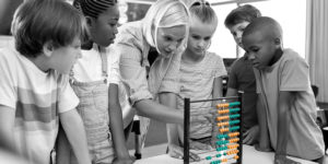 blond lady showing stupid children how to use an outdated abacus